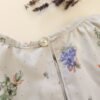 Blouse volantée motif floral gégé gris et bleu 80 cm focus sur le bouton upcyclé