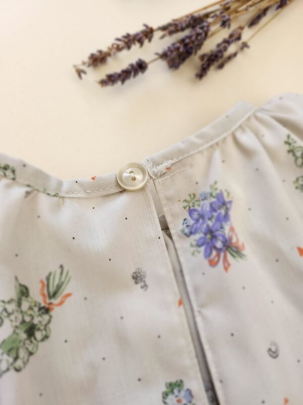 blouse_volante_fille_80cm_calin_tout_doux Blouse volantée motif floral gégé gris et bleu 80 cm focus sur le bouton upcyclé